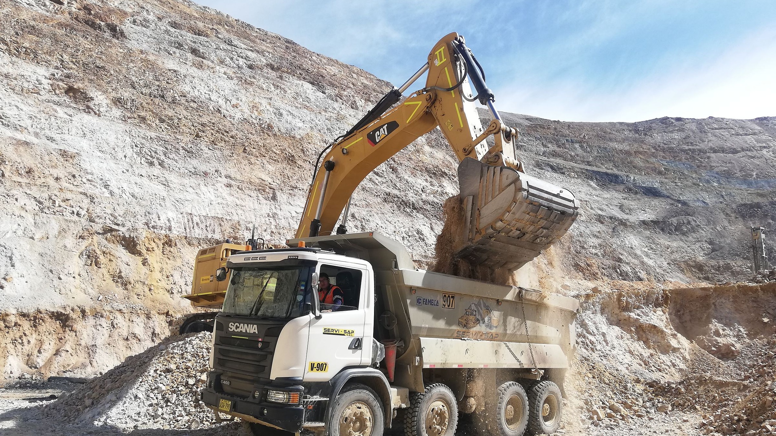 Yellow excavator loading a dump truck in an open-pit quarry